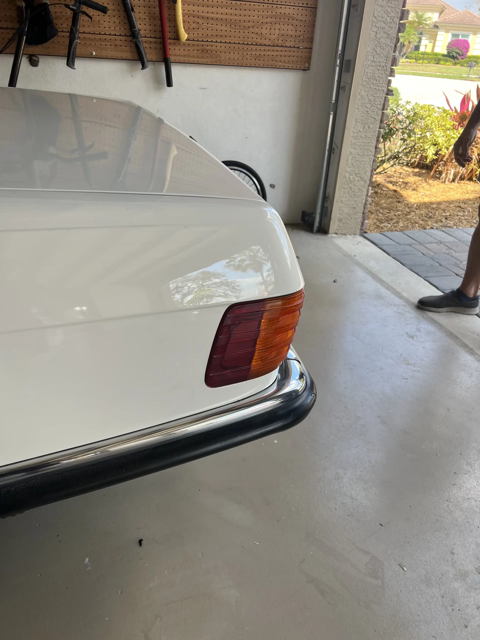 The back of a white Mercedes inside a garage after being repaired. 